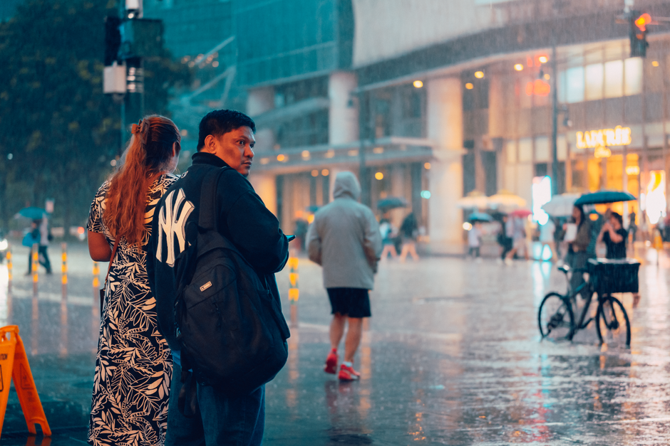 People crossing the street in the rain at a busy intersection in Makati City, Philippines.