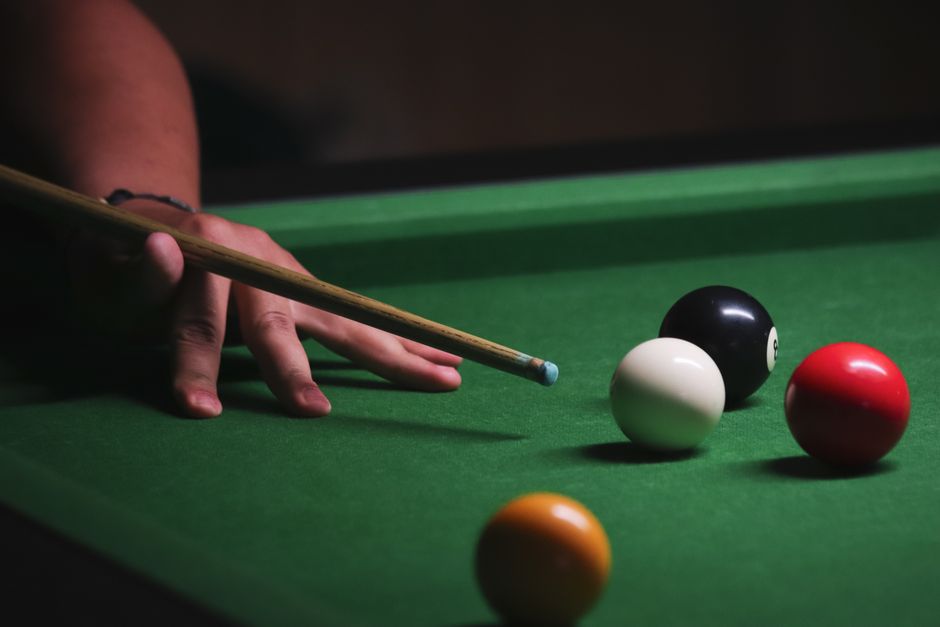 Person playing billiards, focusing on precise hand positioning and cue technique.