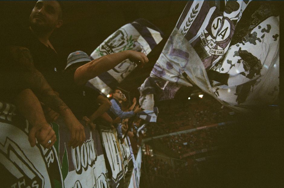 A lively crowd waving flags and cheering during an exciting sports event in a stadium.