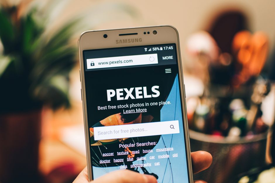 A close-up view of a smartphone displaying the Pexels website screen for stock photo searches.