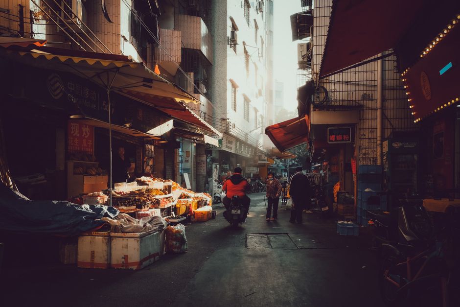 A busy street market in Guangzhou, China, captured at dusk, with locals shopping and vibrant lighting.