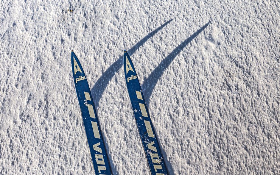 Pair of blue skis casting shadows on snow. Winter sports concept.