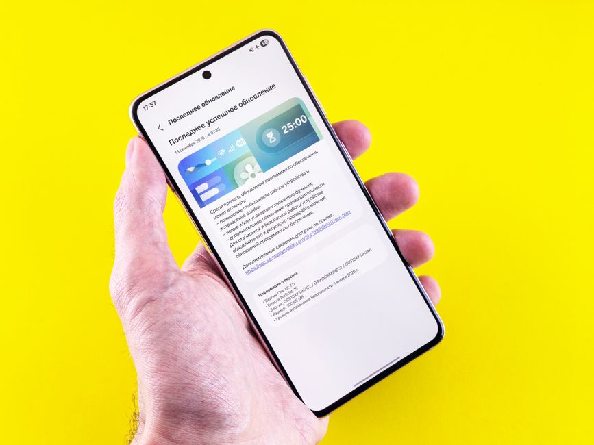 A smartphone displaying an update notification held by a person's hand against a bright yellow background.